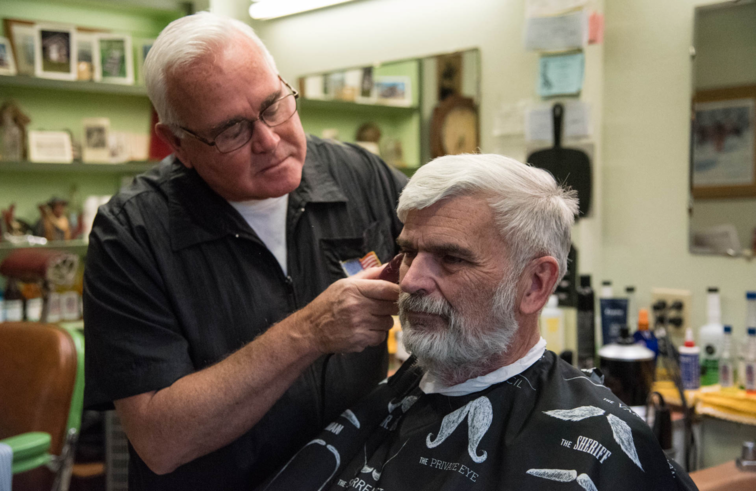 Image of Lin holding up a mirror for the old man to see his new haircut