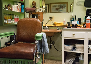Image of a brown and green chair in the corner of Lins barber shop